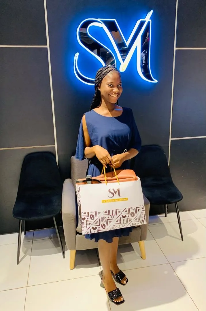Cliente SurMesure avec son sac SM dans le showroom de Douala