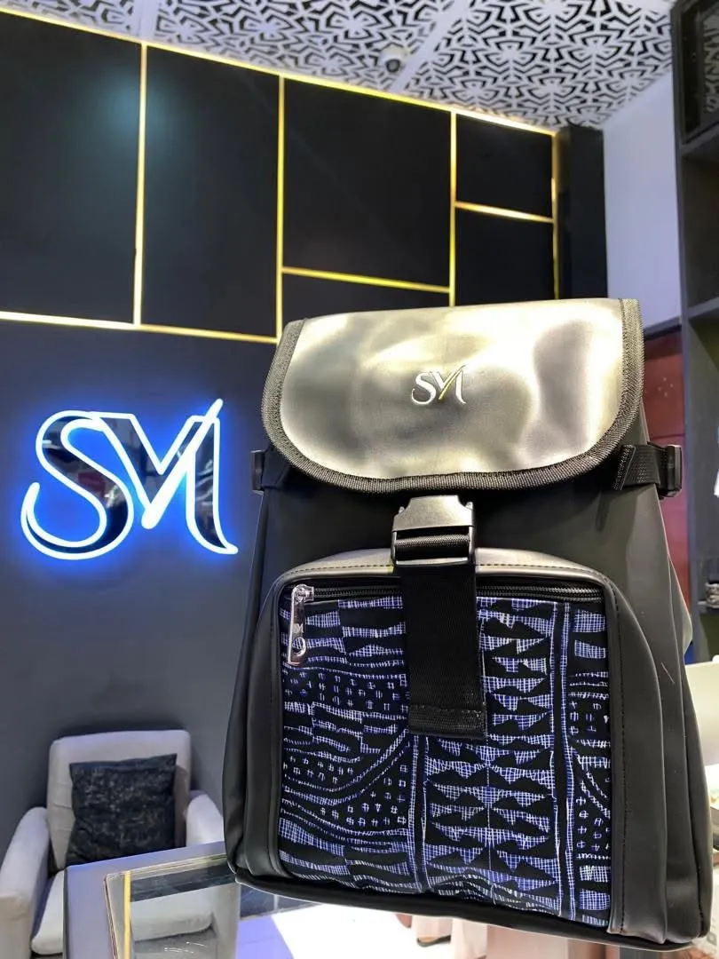 Sac à dos SurMesure en cuir noir et tissu africain tissé, devant le logo SM lumineux